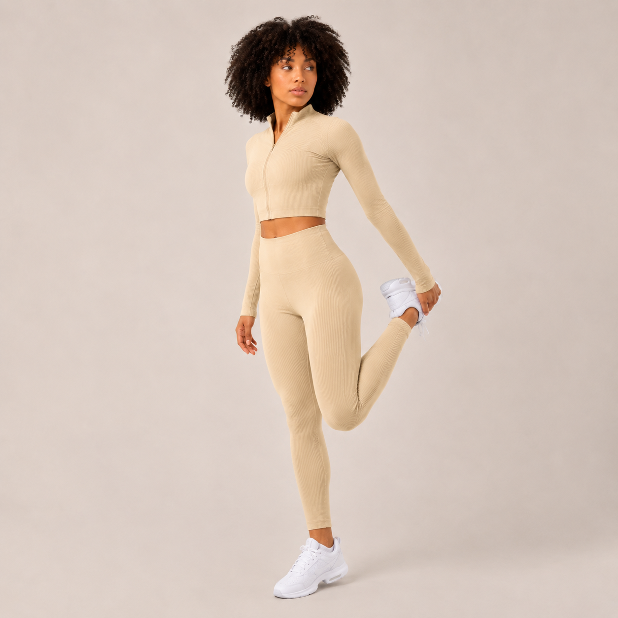 Model wearing the cream Fitfigura Studio Set – Soft Flow Form in a leg-lift pose, highlighting the flexible activewear fit.