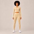 Model wearing the Fitfigura Studio Set – Soft Flow Form in cream, featuring a zip-front long sleeve crop top and matching leggings, shown from the front.