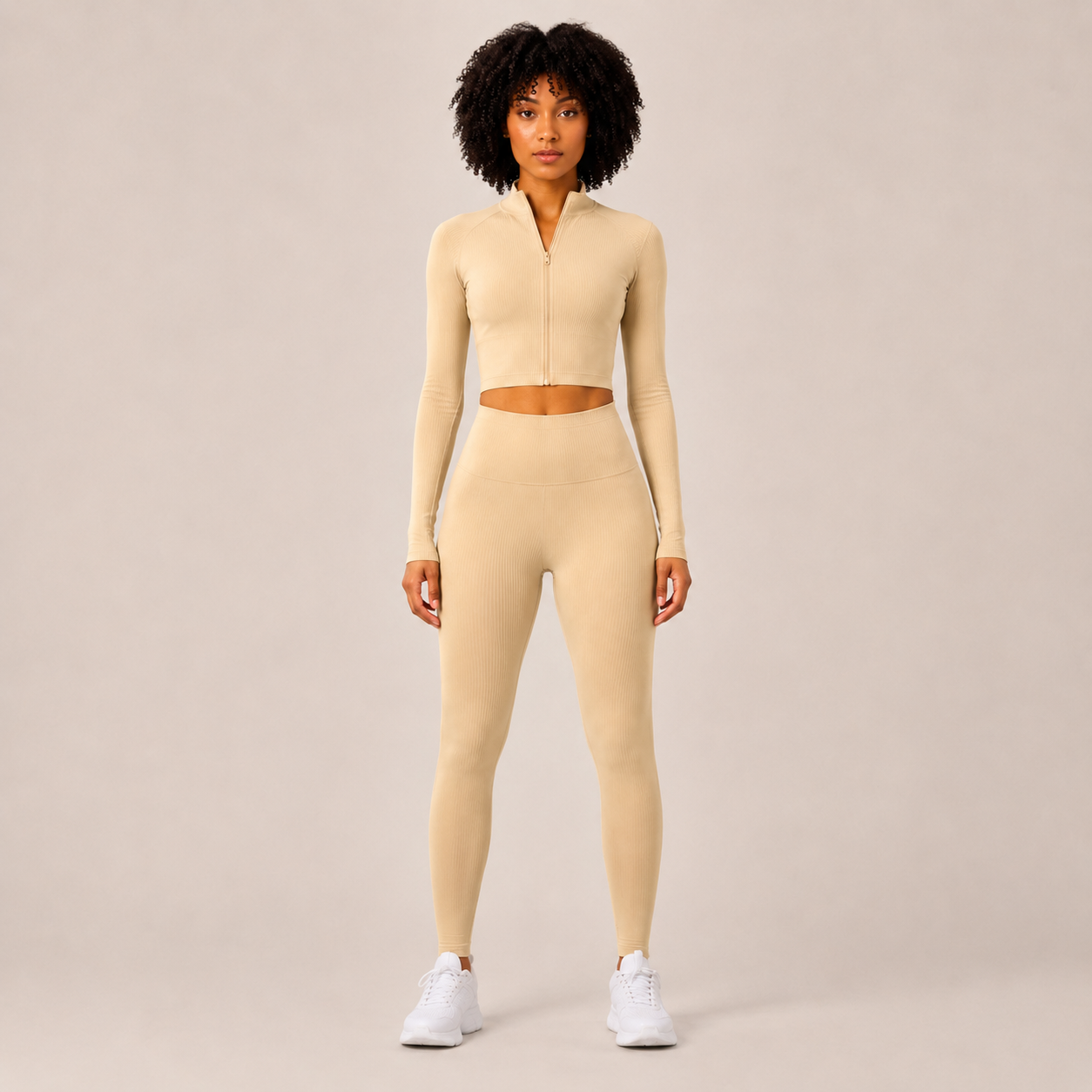 Model wearing the Fitfigura Studio Set – Soft Flow Form in cream, featuring a zip-front long sleeve crop top and matching leggings, shown from the front.