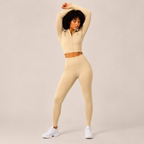 Model posing in the Fitfigura Studio Set – Soft Flow Form in cream with arms raised, showing the smooth stretch fit and coordinated silhouette.