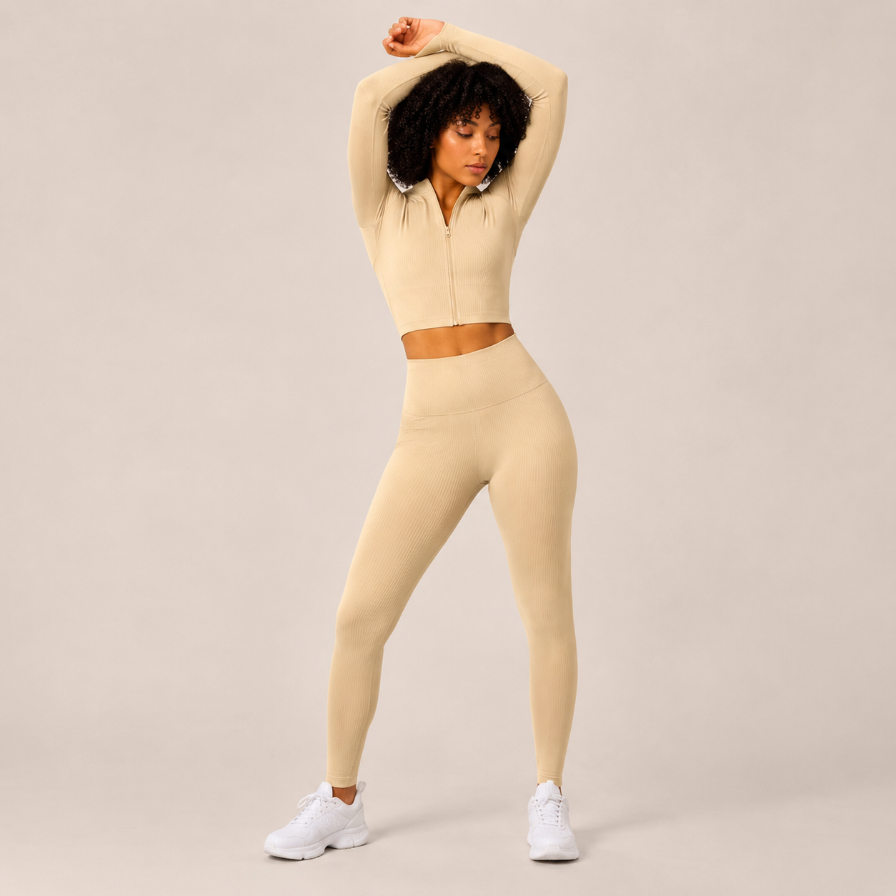 Model posing in the Fitfigura Studio Set – Soft Flow Form in cream with arms raised, showing the smooth stretch fit and coordinated silhouette.