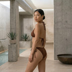Three-quarter view of the model wearing the brown Fitfigura Support Bikini – Performance Form, showing the shape and fit from an angled perspective.