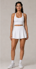 Model wearing the Fitfigura Sway Bra Tank Set in white, featuring a bra tank top and matching pleated skirt, shown from the front.