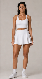 Model wearing the Fitfigura Sway Bra Tank Set in white, featuring a bra tank top and matching pleated skirt, shown from the front.