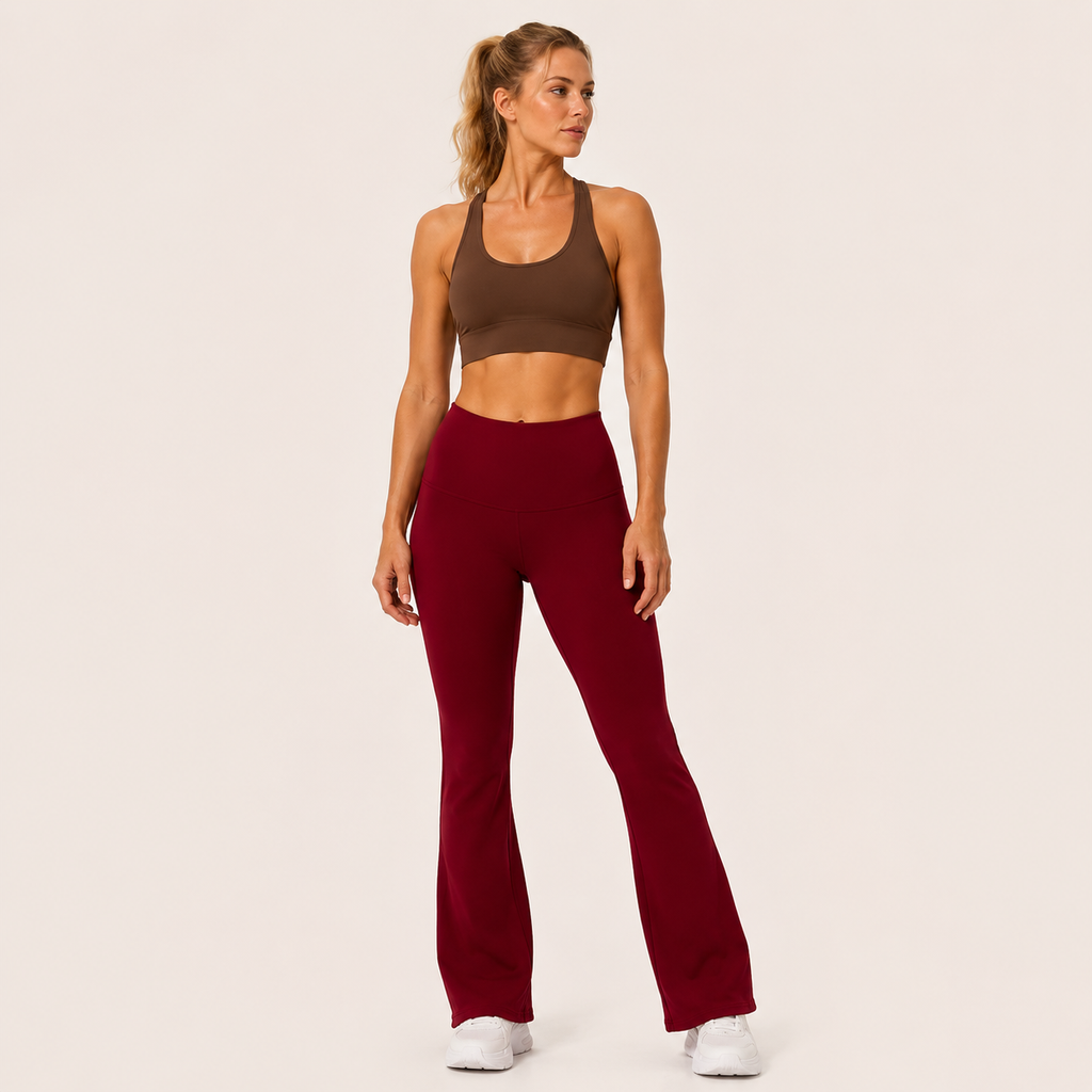 Full-body studio view of the burgundy Fitfigura Women’s Booty Boost Yoga Flare Pant styled with a matching activewear top and white sneakers.