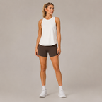 Model wearing the Fitfigura Women's in Motion Seamless Tank Top in white with dark shorts and white sneakers, shown from the front.