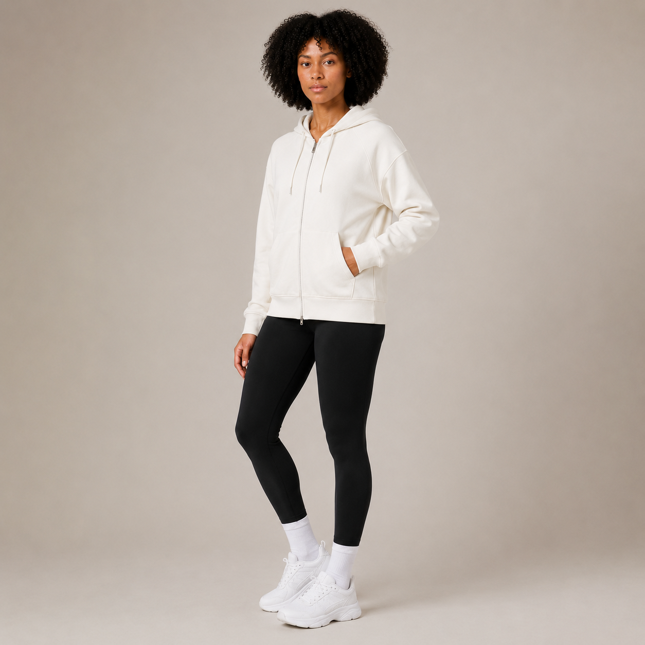 Model posing in the Zip Hoodie – Utility Form, highlighting the white zip-front hoodie and fitted activewear styling.