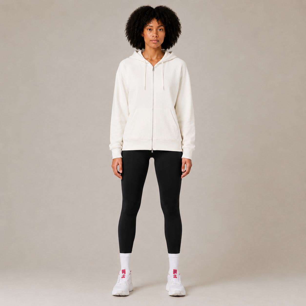 Model wearing the white Zip Hoodie – Utility Form with black leggings and white sneakers, shown from the front.