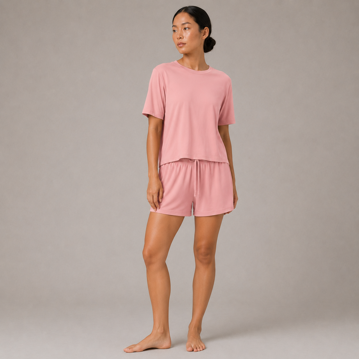 Model wearing the FitFigura Sculpt LoungeWear Set in Paradise Pink with a relaxed tee and matching lounge shorts, three-quarter view.
